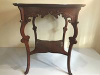 Full frontal view showing carved apron decoration and curved legs of the wooden table.