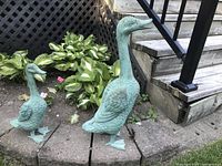 Front view of two metal duck statues placed on garden edging