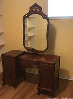 Front view of the wooden vanity with large ornate mirror showing two drawer columns and central curved drawer