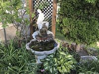 Front view of complete tiered fountain installed among plants