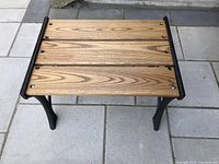 Top view showing three wooden slats with circular metal fasteners on wrought iron frame.