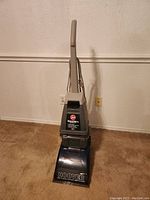 Full view of upright Hoover steam cleaner showing the handle, tank, and base on carpet.