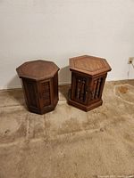 Two hexagonal wooden end tables side by side on carpet, one with a closed solid top and the other with double front doors closed.
