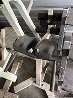 Full view of Nautilus back extension machine showing padded knee and foot rollers and solid white frame.