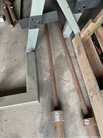 Photo of single rusted metal barbell lying on floor between metal framework and wooden pallet