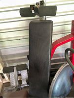 Top view of the black padded backrest and foam rollers at the top of the exercise bench.