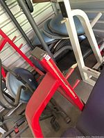 Front angled view of the red flat bench press showing worn black pad and metal frame with weight plate holders.