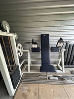 Front view of navy blue and white lat pullover exercise machine with seat, backrest, arm pads, and cables visible.
