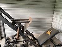 View of the entire leg press machine showing the black metal frame, padded back rest with tear, footplate, and handles.