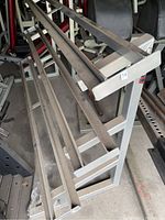 Image shows a three-tier metal dumbbell rack with a gray finish, heavy construction designed to store dumbbells, showing dust and rust spots needing cleaning.