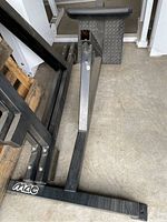 Photo showing a black metal frame part of the reverse hyper machine with a padded cylindrical section, no visible damage but some dirt and wear.