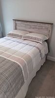 Queen size bed fully made showing headboard and integrated linens