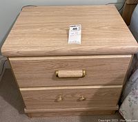 Front view showing two drawers with gold-colored handles and wood grain finish.
