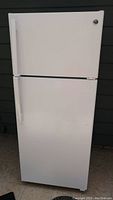 Front view of white General Electric refrigerator showing top freezer door and bottom refrigerator door with vertical handles.