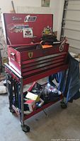 Snap-On red tool box on rolling cart, several drawers, stickers on box