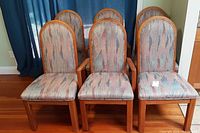 Front view of six wooden dining chairs with upholstered seats and backs, showing fabric pattern and wood grain.