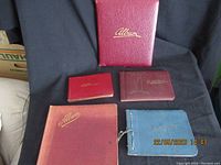 Five different autograph albums of various sizes and colors against a black fabric.