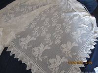 Full view of the handmade crochet tablecloth laid flat, showing bird and floral motifs with scalloped edges.