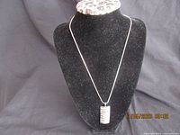 Full front view of the pendant on black display bust showing necklace length and pendant size.