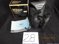 Photo of Nikon Travelite IV 9x25CF binoculars, carrying case, manual, and original box arranged on a black backdrop showing front view.