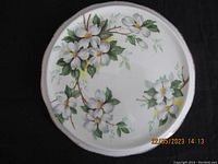 Full view of the round trivet with dogwood flower artwork.