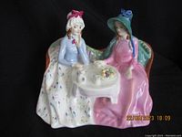 Front angled view of Royal Doulton Afternoon Tea figurine showing two women sipping tea on a floral couch with a table and tea set in front of them.
