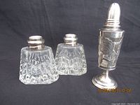 Front view of two short glass shakers and one tall shaker with silver overlay