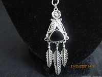 Close-up of the pendant showing silver work, black onyx stone, and three silver feather dangles.