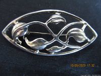 Front view of sterling silver vintage brooch showing leaf motif design and openwork oval shape.