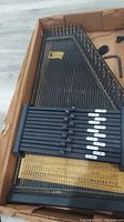 Black Oscar Schmidt International autoharp with chord bars, strings, and tuning pins visible inside the box.