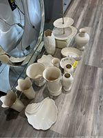 Wide view showing the full collection of 14 white Lenox porcelain vases, dishes, plates, and serving tray items arranged on the floor.