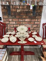 Full view of Lenox Christmas themed dishware arranged on red table, showing large platter, bowls, and vases.