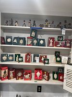 Three bottom shelves displaying boxed Lenox porcelain ornaments and one Shiny Brite topper on left
