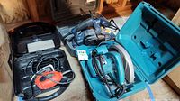 Photo of the lot showing Ryobi planer in case, Makita circular saw in case, and Black & Decker Mouse sander on the floor.