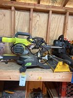 Side view of Ryobi 14-inch electric miter saw with visible blade, handle, and base labeled 14 inches.