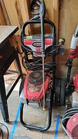 Simpson power washer showing gun, hose, and frame with wheels in a garage environment.