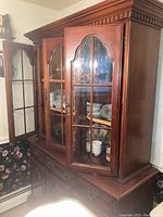 China cabinet showing front with glass doors open, wooden shelves and interior light visible. Dining dishes inside for scale only and not included.