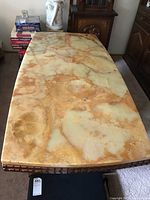 Top surface view of the coffee table showing the thick onyx stone with natural veining in beige and amber tones, and some surface scratches.