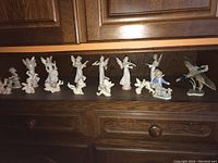 Wide view of all eleven figurines on a wooden shelf including angels, child, and ducks