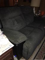 Front angled view of dark gray upholstered reclining loveseat by La-Z-Boy with padded armrests and tufted cushions.