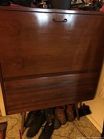 Front closed view of wood secretary desk showing drop front panel with small metallic handle and wood grain finish. Four tapered legs visible.