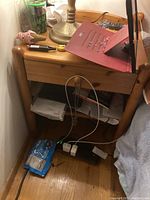 Wooden side table with drawer and lower shelf viewed with items on top and underneath showing size and condition.