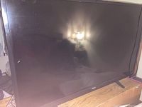 Photo of Sanyo 50 inch TV screen on stand showing full front view and reflective display surface with minor smudges.