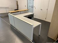 Front and side view showing entire reception desk assembled with white panels, work surface and light wood counter.