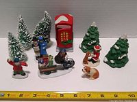 Photo showing entire lot including red phone booth, three ceramic green Christmas trees, three small artificial snow trees, and four various figurines of people and animals on snow bases.