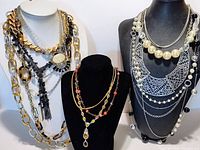 Front view of multiple layered necklaces on display velvet busts showing various styles and materials
