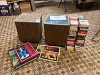 Overview of two wooden cabinet units for Wynford Hall 8-track player and speaker, with stacks of over 60 8-track cassettes.