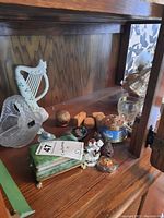 Photo showing various items including the alabaster box, a crystal bowl, small wooden boxes, and porcelain figurines inside a wooden cabinet.