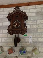 Front view of cuckoo clock showing ornate carved wooden housing and clock dial with Roman numerals.