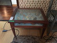 Front view of wood and glass display table showing topside glass panel and wooden frame with visible figurines inside